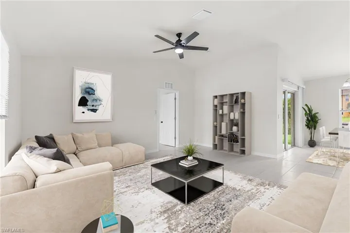Tiled living room featuring ceiling fan and vaulted ceiling