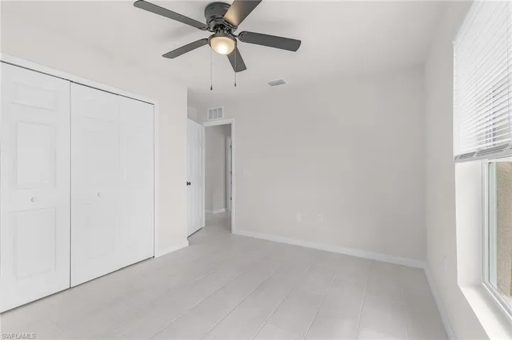 Unfurnished bedroom featuring light tile patterned flooring, ceiling fan, and a closet