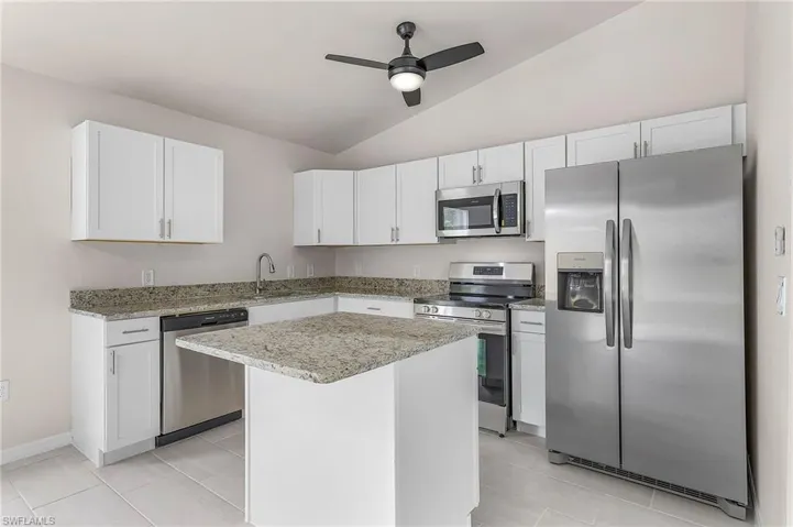 Kitchen featuring appliances with stainless steel finishes, ceiling fan, lofted ceiling, and white cabinets