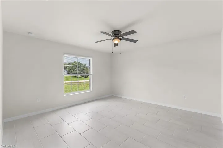 Empty room with ceiling fan and light tile patterned floors