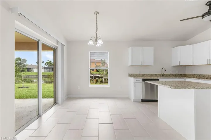 Kitchen featuring stainless steel dishwasher, white cabinets, ceiling fan with notable chandelier, and light tile patterned floors