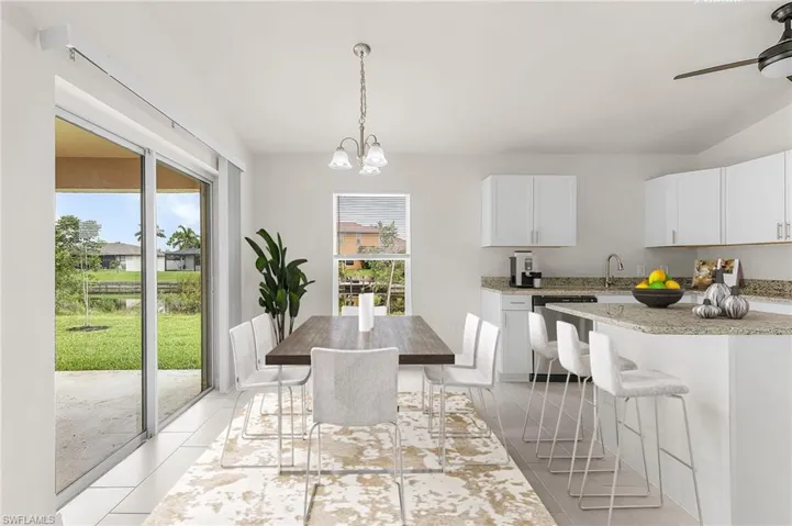 Kitchen featuring stainless steel dishwasher, light tile patterned floors, white cabinets, and plenty of natural light
