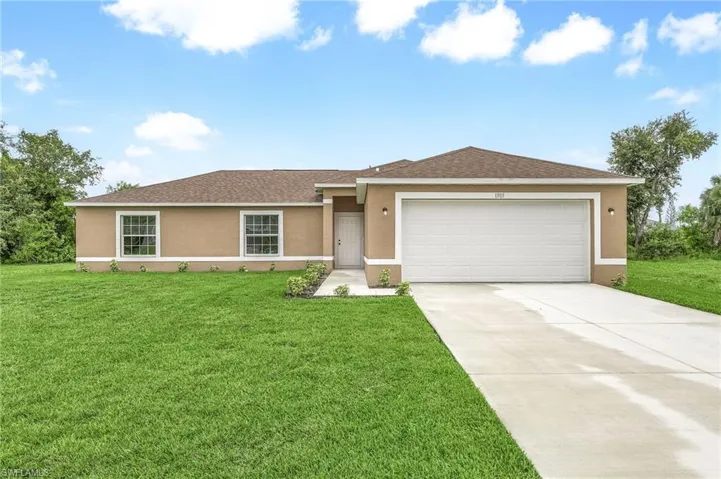 Ranch-style home featuring a garage and a front lawn