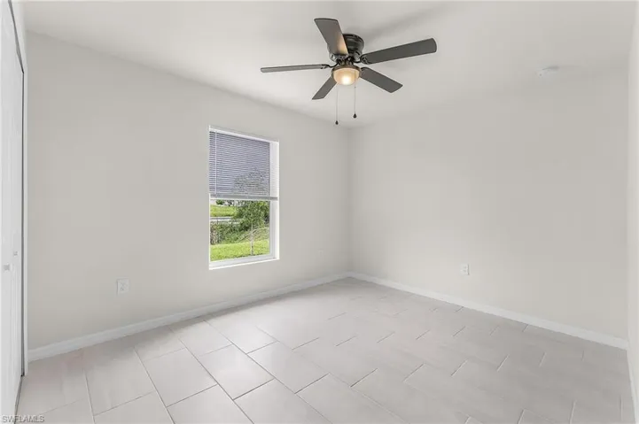 Empty room featuring light tile patterned floors and ceiling fan