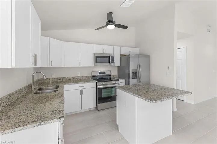 Kitchen with white cabinetry, a kitchen island, ceiling fan, appliances with stainless steel finishes, and sink
