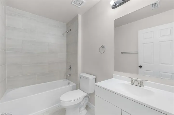 Full bathroom featuring tile patterned floors, vanity, tiled shower / bath combo, and toilet