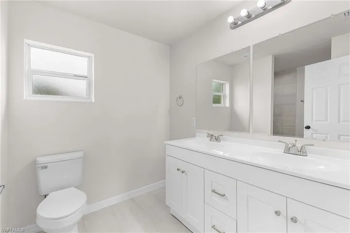 Bathroom featuring tile patterned flooring, dual vanity, and toilet