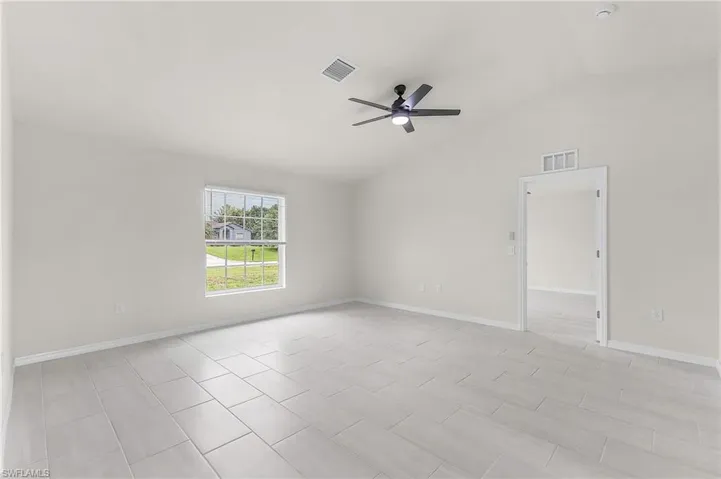 Unfurnished room with light tile patterned flooring, vaulted ceiling, and ceiling fan