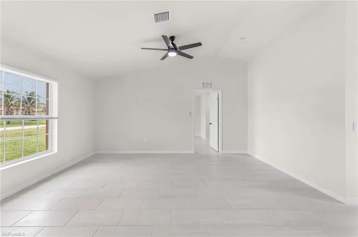 Tiled empty room featuring ceiling fan and vaulted ceiling