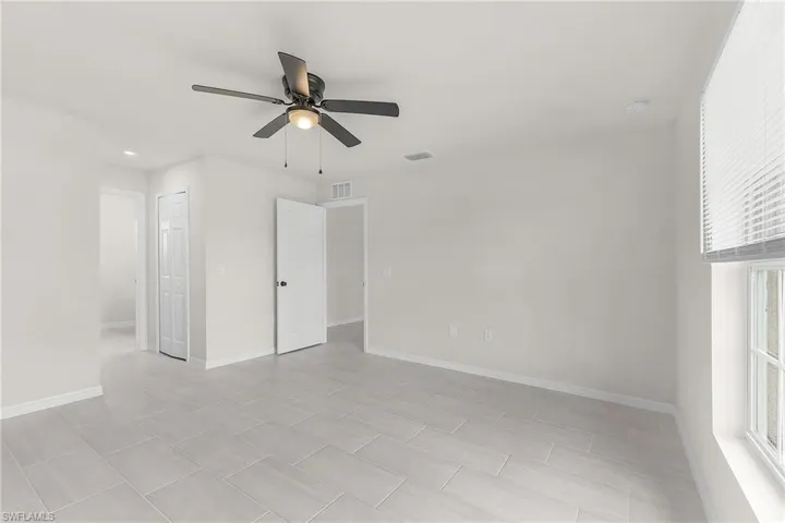 Empty room with light tile patterned floors and ceiling fan