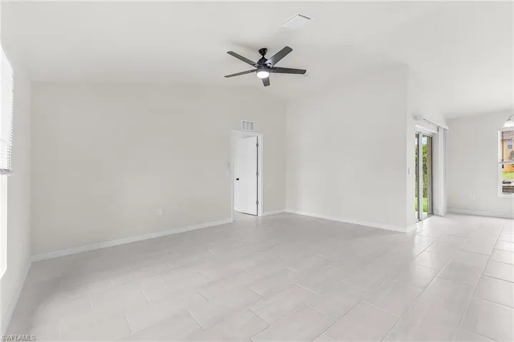 Tiled spare room featuring high vaulted ceiling and ceiling fan