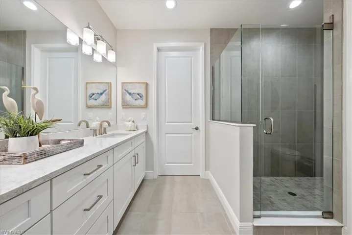 Bathroom featuring walk in shower, dual sinks and recessed lighting