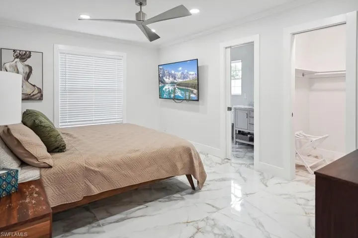 Bedroom with crown molding, recessed lighting, connected bathroom, a ceiling fan, and light marble finish floors