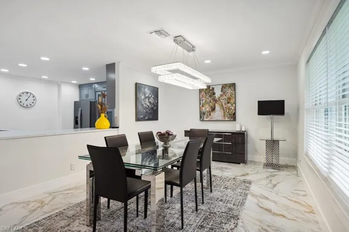 Dining area featuring light marble finish flooring, a chandelier, crown molding, and recessed lighting