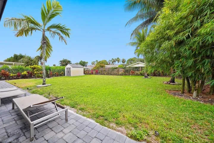 Fenced backyard featuring a storage unit and a patio area