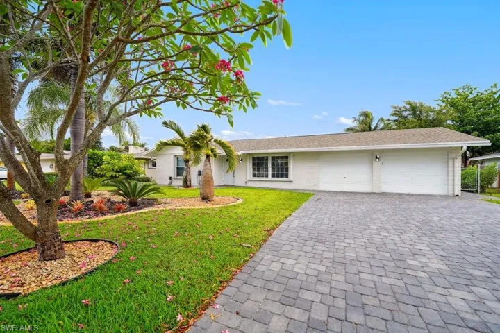 Single story home featuring a garage, brick siding, decorative driveway, a front lawn, and a shingled roof