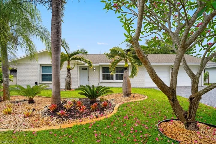 Single story home with brick siding, a front yard, a garage, driveway, and a shingled roof