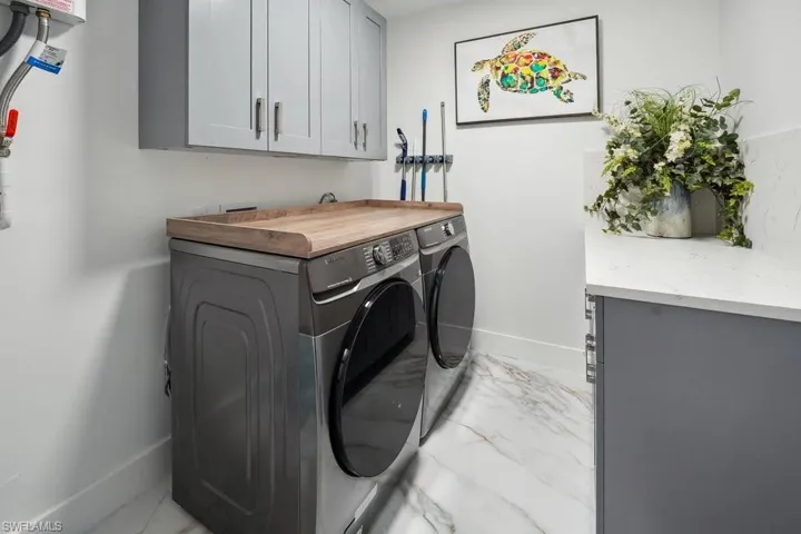 Washroom featuring cabinet space, light marble finish floors, and separate washer and dryer