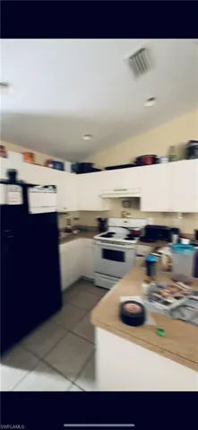 Kitchen with white range with electric cooktop and light tile flooring
