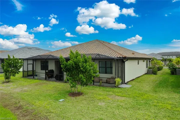 Rear view of house featuring  lovely landscaping and large lanai