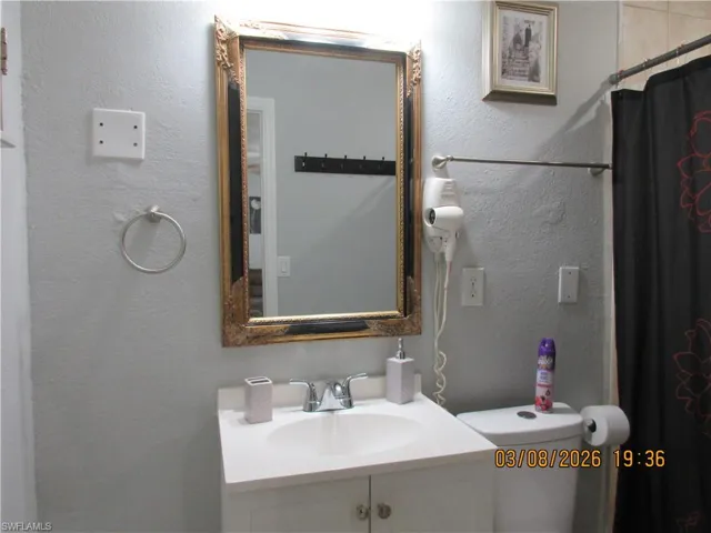 Full bathroom featuring a textured wall, vanity, and curtained shower