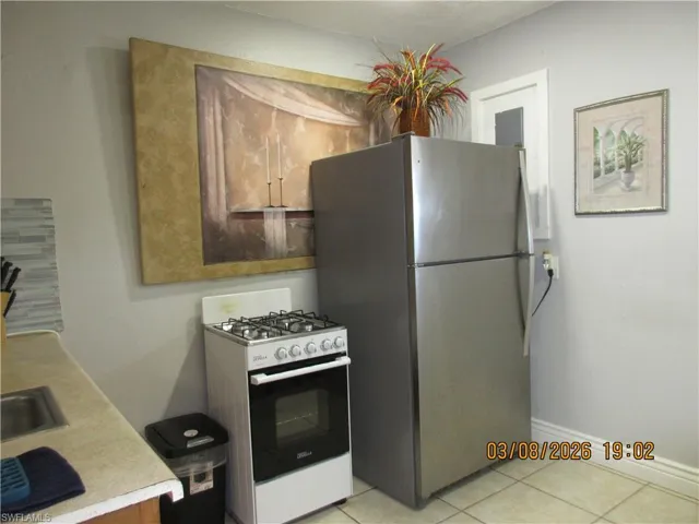 Kitchen featuring range with gas cooktop, freestanding refrigerator, light tile patterned flooring, and wood finish cabinets