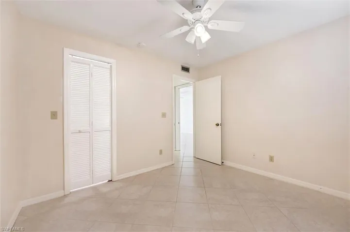 Unfurnished bedroom featuring a ceiling fan, light tile patterned floors, and a closet