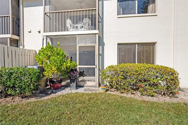 Entrance to property featuring a sunroom, stucco siding, and a lawn
