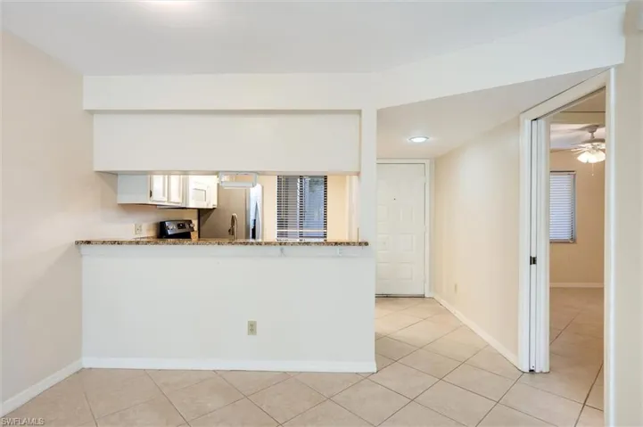 Kitchen featuring light stone countertops, white cabinets, ceiling fan, and light tile patterned flooring