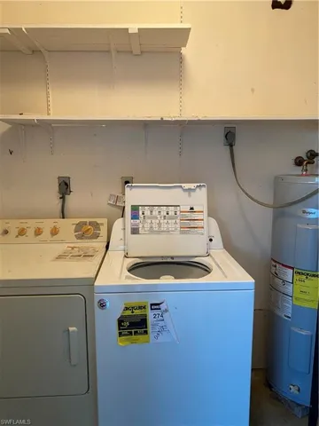 Laundry area featuring water heater, separate washer and dryer, and concrete flooring