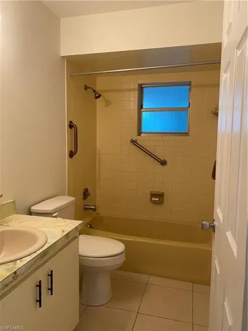 Full bath with vanity, washtub / shower combination, and light tile patterned floors