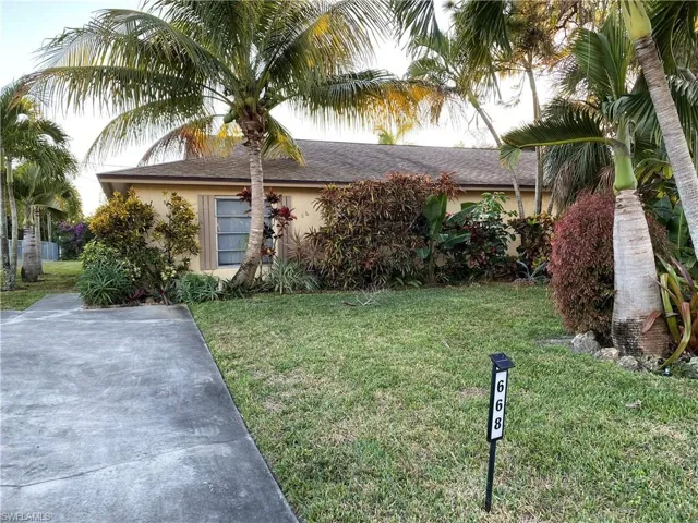 Single story home featuring a front yard, stucco siding, and roof with shingles