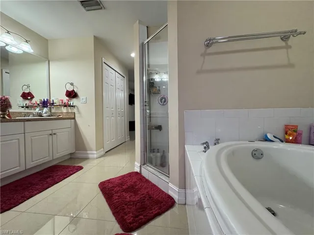 Bathroom featuring vanity, baseboards, visible vents, a shower stall, and a bath