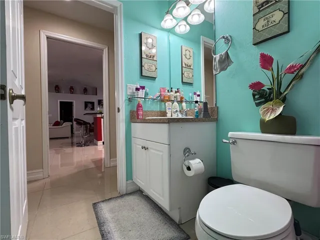 Half bathroom with tile patterned floors, baseboards, toilet, and vanity