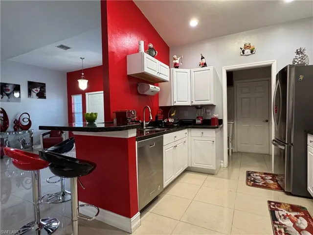 Kitchen with visible vents, a sink, white cabinetry, stainless steel appliances, and light tile patterned floors