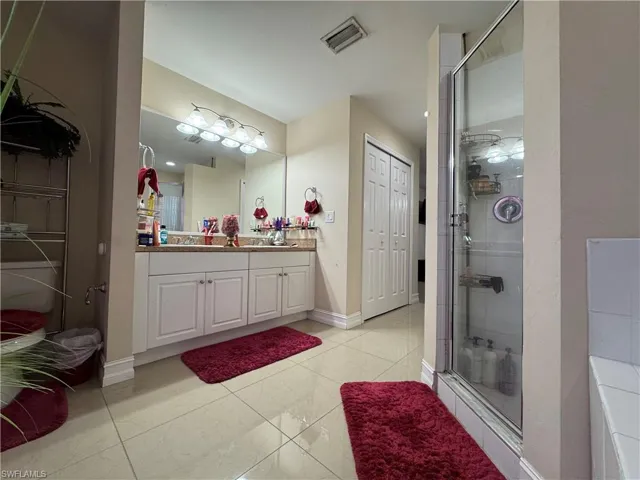 Full bath featuring vanity, a shower stall, baseboards, and visible vents