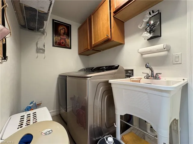 Laundry area featuring a sink, cabinet space, baseboards, and washer and clothes dryer