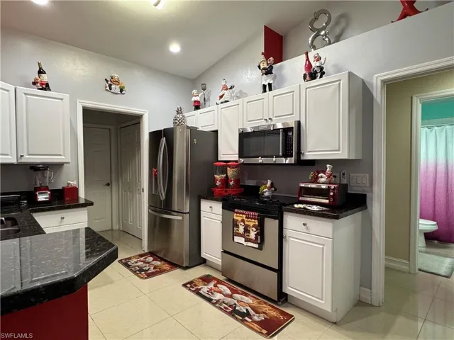 Kitchen featuring white cabinetry, a toaster, light tile patterned floors, and stainless steel appliances