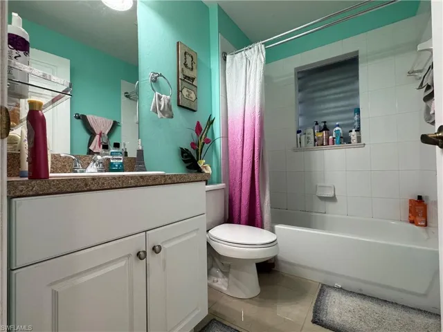 Bathroom featuring vanity, tile patterned floors, toilet, and shower / bathtub combination with curtain