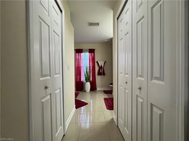 Corridor with light tile patterned floors, baseboards, and visible vents