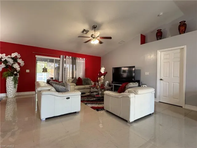 Living room featuring lofted ceiling, marble finish floor, and ceiling fan