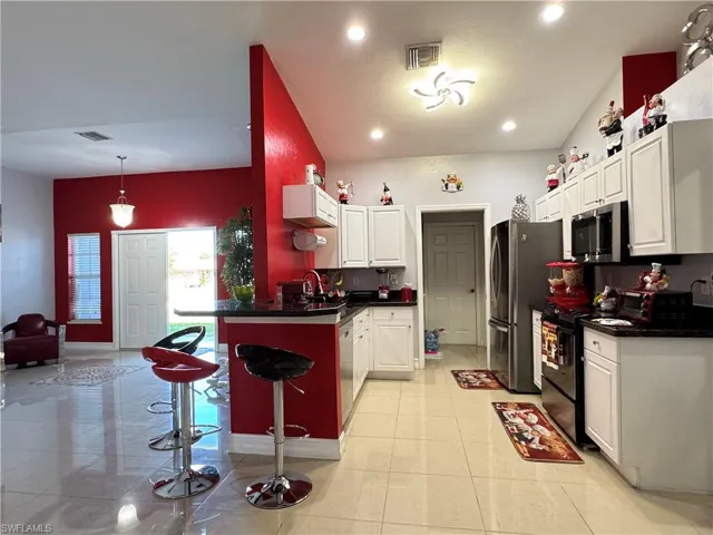 Kitchen featuring visible vents, dark countertops, white cabinetry, stainless steel appliances, and light tile patterned floors