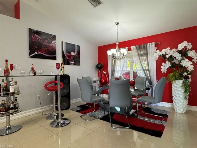 Tiled dining area featuring visible vents, baseboards, an inviting chandelier, and vaulted ceiling