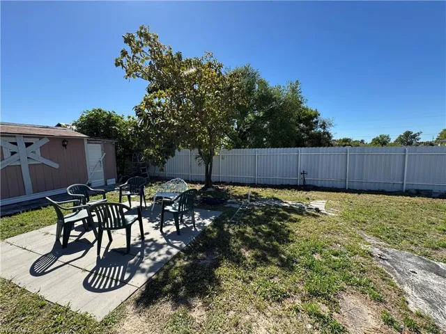 View of yard featuring a storage unit, an outdoor structure, a fenced backyard, and a patio area