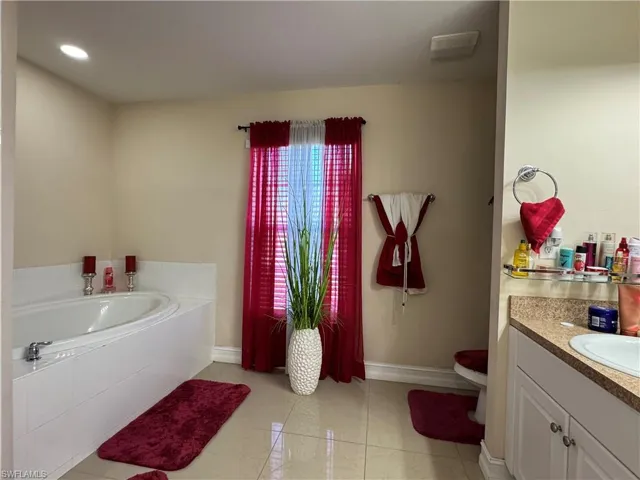 Full bathroom with tile patterned flooring, a bath, vanity, and baseboards