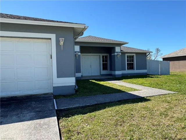 View of front of home featuring fence, stucco siding, a shingled roof, a front lawn, and a garage