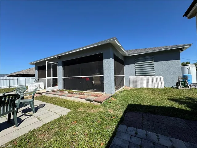 Back of property featuring a patio area, stucco siding, a yard, and a sunroom