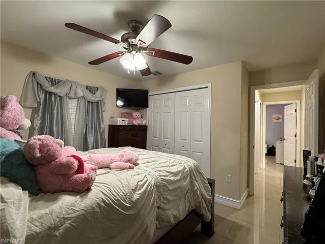 Bedroom featuring light tile patterned floors, a ceiling fan, visible vents, baseboards, and a closet