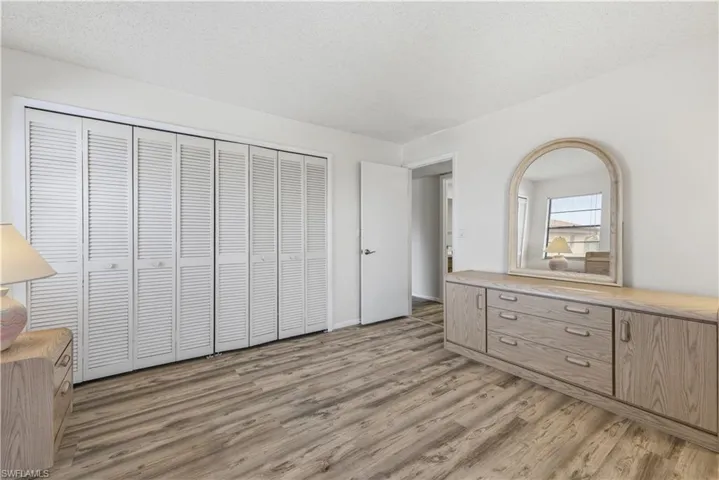 Bedroom featuring wood-finish flooring and a wall of louvered bi-fold closet doors