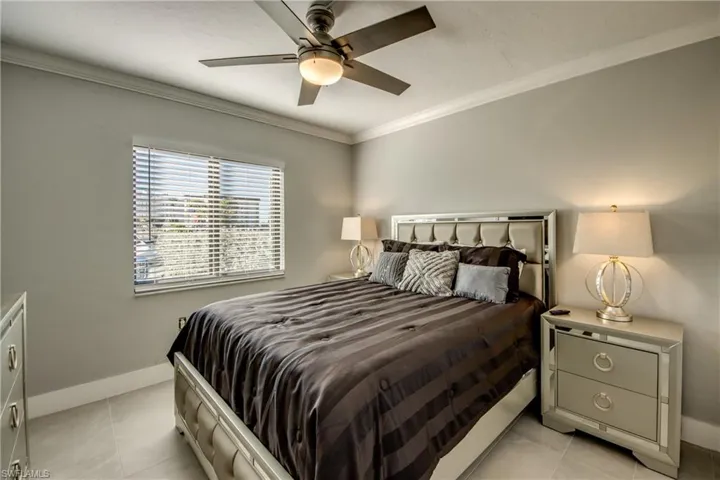 Bedroom with ornamental molding, ceiling fan, and light tile patterned floors